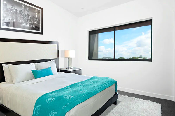 Cozy bedroom with a neatly made bed, bed lamp, window view