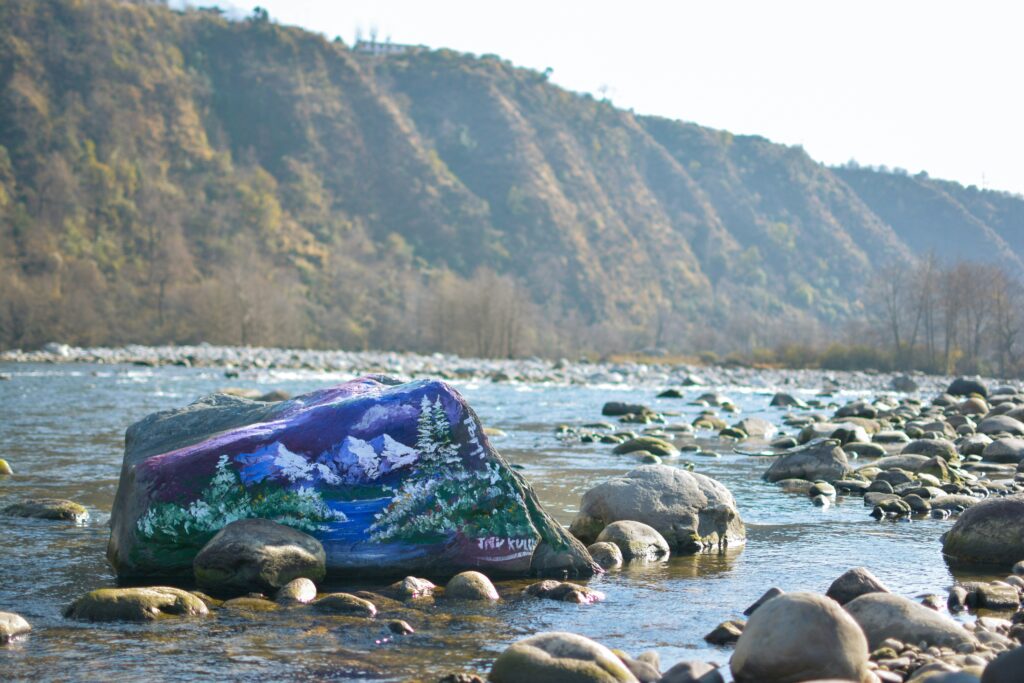 Manali tourist place with clear water and small stones surrounded by mountains